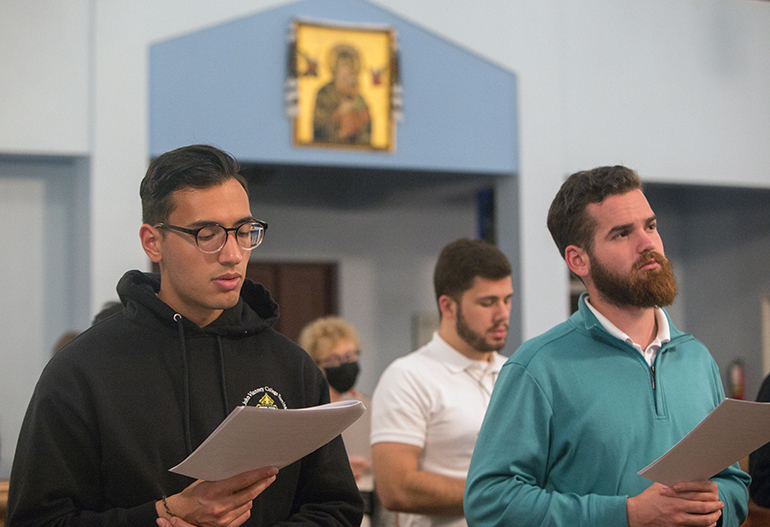 Seminarians, from left, Andrew Zbedics, Andres Papa and Spencer Grant recite prayers during the Moleben to the Mother of God held March 9, 2022 at Assumption of the Blessed Virgin Mary Ukrainian Catholic Church in Miami. The church has been holding the nightly prayers for peace and an end to the war in Ukraine since Russia's invasion.