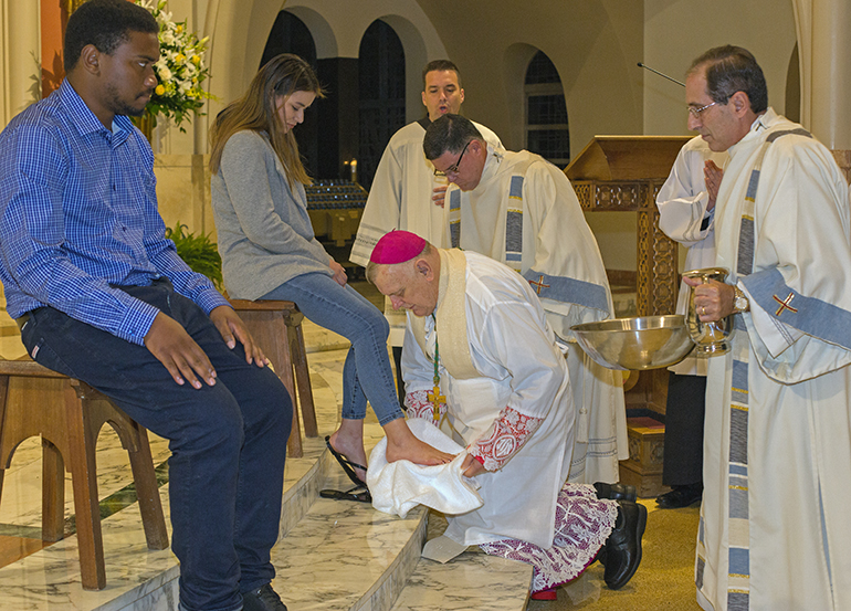 Archbishop Thomas Wenski dries the feet of catechumen  Cristel Rodriguez during Holy Thursday Mass at St. Mary Cathedral, April 14, 2022.