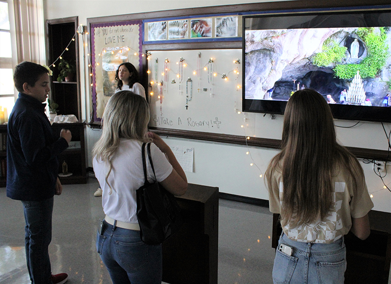 Visitors to Little Flower School in Hollywood pray a Hail Mary in the school's religion classroom, which had been converted into the grotto at Massabielle, in Lourdes, France, where the Virgin Mary appeared to St. Bernadette. On May 18, 2022, the second floor of Little Flower School was converted into a "pilgrimage to Lourdes experience" showcasing different projects across curriculums created by middle school students, all relating to the apparition of the Virgin Mary to St. Bernadette at Lourdes.