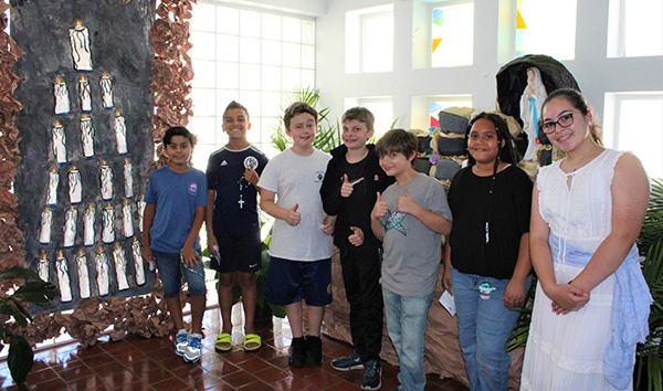 Students from Little Flower School in Hollywood pose by the replica of the Massabielle Grotto they helped make for the "pilgrimage to Lourdes experience" they hosted at their school on May 18, 2022. The grotto, as well as other projects across different curriculums, were on display for family and friends for the day.