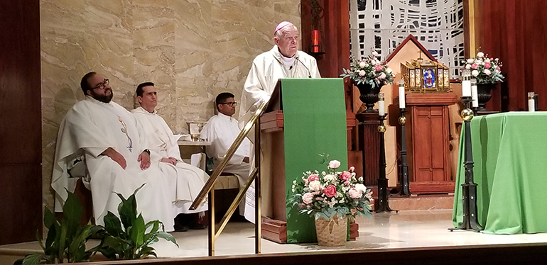 Archbishop Thomas Wenski preaches the homily during the July 26, 2022 Mass marking the 45th anniversary of the death of Miami's founding bishop, Coleman Carroll. Behind him, from left, are Father Matthew Gomez, archdiocesan vocations director; Father Juan Carlos Salazar, administrator of St. Martha Parish; and seminarian Milton Martinez.