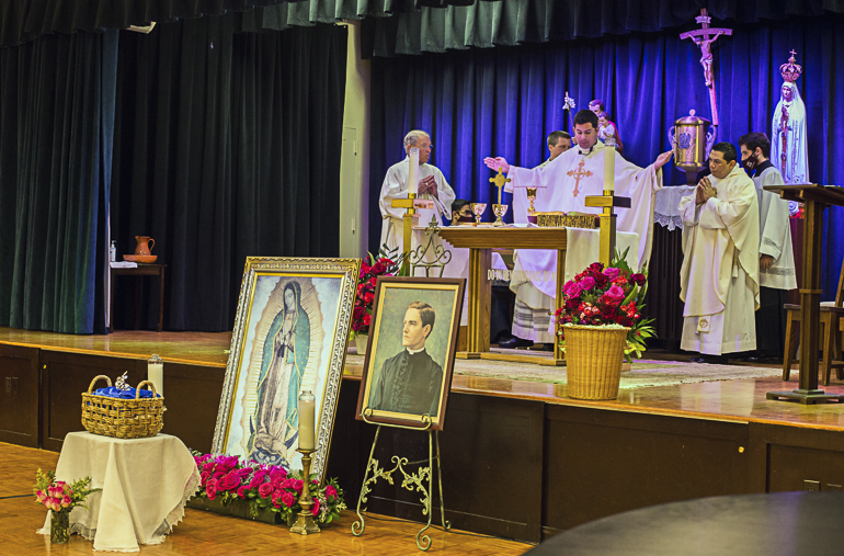 Father Enzo Rosario Prendes, Sts. Peter and Paul parochial vicar and Knights of Columbus archdiocesan chaplain, celebrates Mass at Aug. 14, 2022, at St. Hugh Parish in Coconut Grove, with the Silver Rose and images of Our Lady of Guadalupe and Blessed Father Michael McGivney in front.