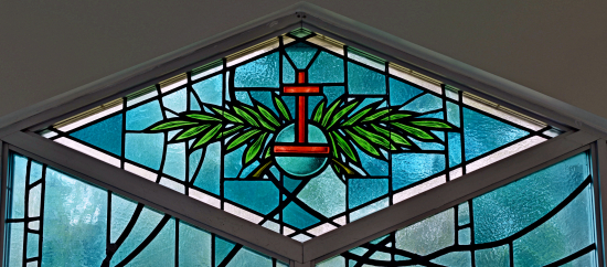 Christ the King is honored in the Palm Sunday window, with an orb standing for rulership of the world. The palms represent the fronds laid at Jesus' feet in the Triumphal Entry.