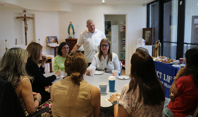 El diácono James Dugard, asignado al Ministerio de Respeto a la Vida, habla con las trabajadoras y voluntarias del ministerio después de la bendición del nuevo centro en Fort Lauderdale, el 13 de agosto de 2022.