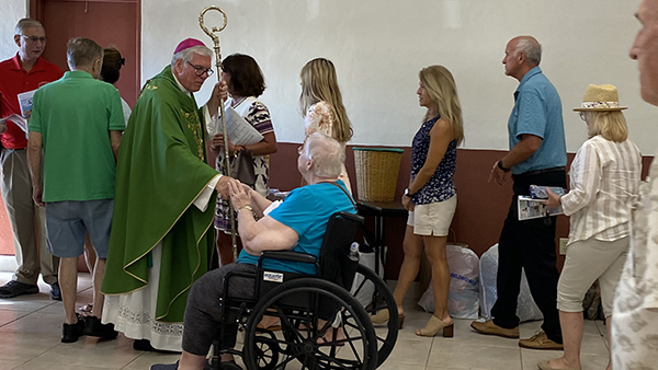 Bishop Frank Dewane of Venice shakes hands with parishioners of Incarnation Parish in Sarasota after celebrating vigil Mass Oct. 1, 2022. Hurricane Ian ravaged parts of the southwest Florida diocese. Incarnation parishioners gathered for Mass in the parish hall as part of the church roof was blown off.