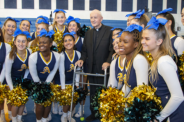 Cheerleaders gather around Msgr. Vincent Kelly, who has been associated with St. Thomas Aquinas since 1970, after the school celebrated its 2022 Blue Ribbon designation as an Exemplary High Performing High School, Oct. 3, 2022.