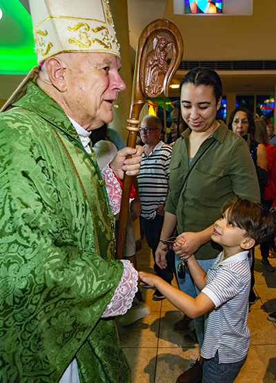 Archbishop Thomas Wenski greets Ada Ramos and her son, Adrian Ramos, 5, a St. Rose of Lima student, after the Mass that kicked off the Miami Shores parish's 75th anniversary celebration, Oct. 9, 2022.