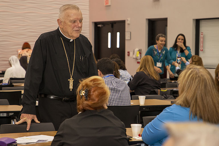 Archbishop Thomas Wenski chats with participants before the start of Bridging the Gap 2022, a professional development day hosted by the offices of Development and Evangelization and Parish Life which brought around 250 parish staff members, volunteers, priests and school principals to Msgr. Edward Pace High School in Miami Gardens, Oct. 11, 2022.