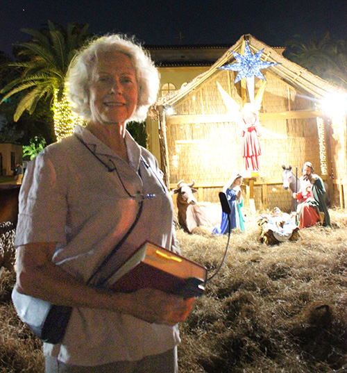 La artista y feligresa Kathleen Staples posa delante del Nacimiento y las estatuas que ha restaurado recientemente en la iglesia Little Flower de Coral Gables. El Nacimiento fue bendecido e inaugurado el 28 de noviembre de 2022.