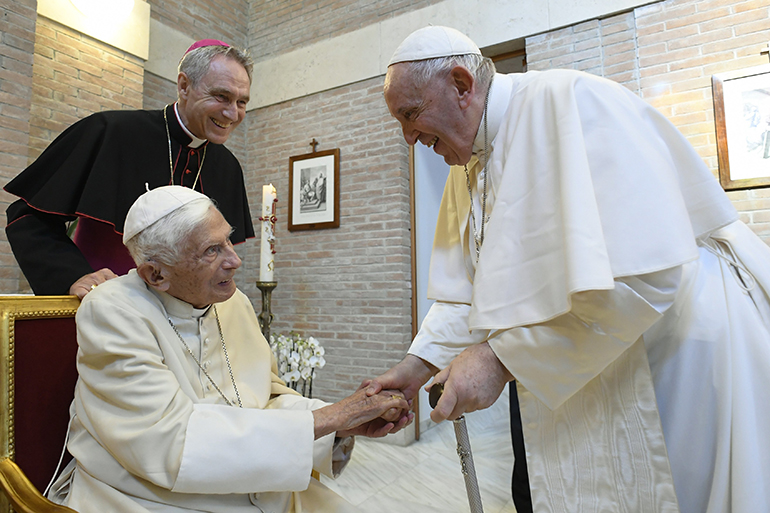 El Papa Francisco saluda al Papa retirado Benedicto XVI en el monasterio Mater Ecclesiae después de un consistorio para la creación de 20 nuevos cardenales en la Basílica de San Pedro en el Vaticano el 27 de agosto de 2022. El arzobispo Georg Ganswein, secretario privado del papa jubilado, observa. (Foto del CNS/Vatican Media)