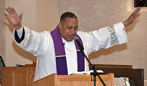 Father Sidney Speaks uses sweeping gestures as he preaches a revival Feb. 9, 2023 at the St. Anthony Chapel of St. Thomas University.