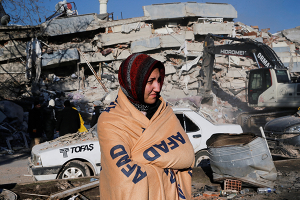 An earthquake survivor stands next to the site of a collapsed building in Kahramanmaras, Turkey, Feb. 8, 2023. The powerful 7.8 magnitude earthquake rocked areas of Turkey and Syria early Feb. 6, toppling hundreds of buildings and killing thousands. (OSV News photo/Dilara Senkaya, Reuters)