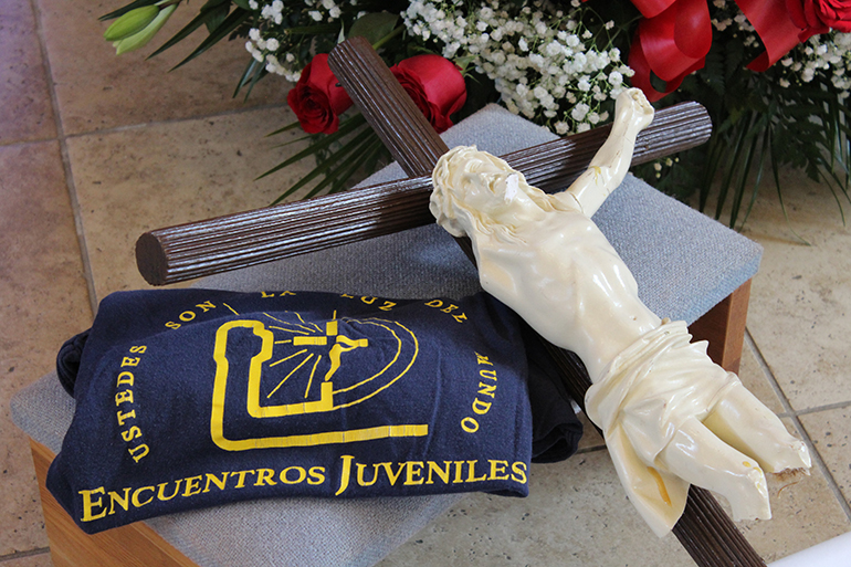 Members of Encuentros Juveniles placed a cross with the "Broken Christ," the movement's t-shirt, and the initiation scroll of Encuentristas (not pictured) in front of the altar at the Chapel of St. Anthony at St. Thomas University in Miami Gardens during a Mass celebrated by Archbishop Thomas Wenski and other priests on Jan. 31, 2023. Encuentros Juveniles, the official youth movement of the Archdiocese of Miami, is celebrating its 50-year anniversary with various activities.