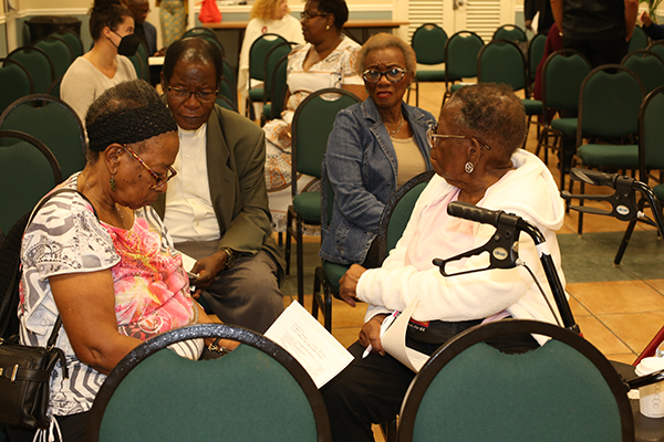 At a break-out session, members of Holy Redeemer Parish in Liberty City discuss some of what they heard during a workshop on Catholic social teaching, held Feb. 20, 2023 at St. Mary Cathedral. From left: Donna Blyden, Father Alexander Ekechukwu, pastor, Doris Brown-Hunt and Millicent Brown-Storr.