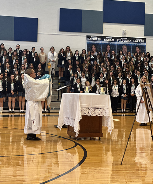 Deacon Louis Phang Sang elevates the monstrance with the Blessed Sacrament during the all-school exposition and benediction held at Our Lady of Lourdes Academy in Miami to mark the start of Holy Week, April 3, 2023.