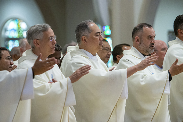 Priests extend their hands during the consecration of the bread and wine at the chrism Mass, celebrated at St. Mary Cathedral, April 4, 2023.