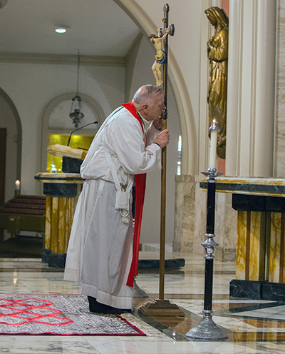 A shoeless Archbishop Thomas Wenski kisses the cross during the Good Friday liturgy at St. Mary Cathedral, April 7, 2023, the only day of the year when Mass is not celebrated.