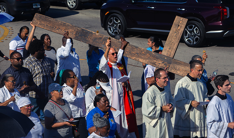 Father Christopher Marino, St. Mary Cathedral's rector,  center, walks alongside parishioners during a Good Friday procession around the cathedral, April 7, 2023.