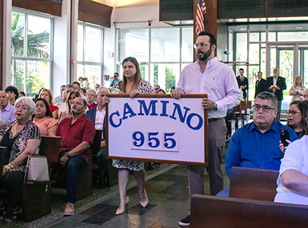 Los esposos Jennifer y Gabriel Cambert presentan un cartel con el número 955, por los retiros que le movimiento Camino del Matrimonio ha realizado hasta ahora, durante la Misa por el 50 aniversario del movimiento, el 16 de abril, en la capilla del Seminario St. John Vianney, en Miami.