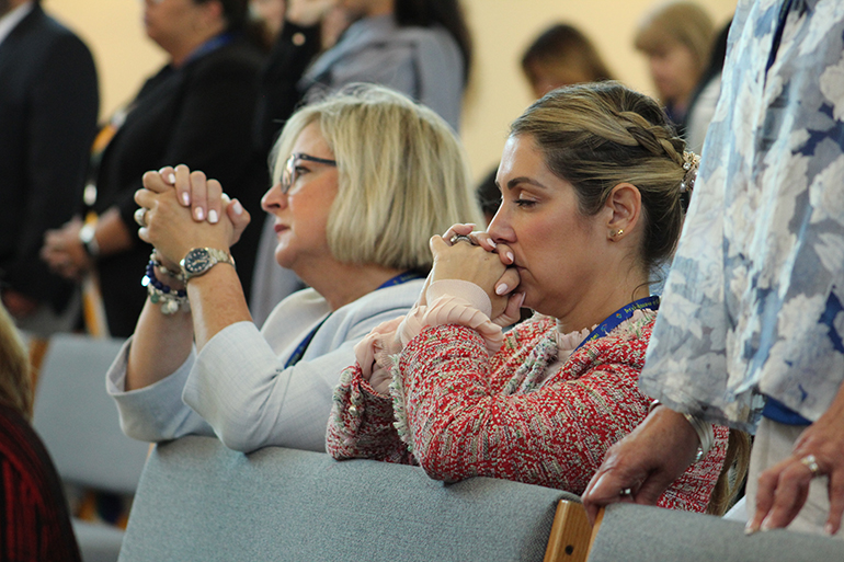 Blessed Trinity School Principal Susy Del Riego prays alongside Good Shepherd School Principal Melissa Hernandez during a Mass at the Archdiocese of Miami Office of Schools' final meeting of principals on April 27, 2023 at Archbishop Edward McCarthy High School in Southwest Ranches.