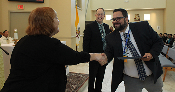 After being recognized for completing his first year as principal of Mary Help of Christians School in Parkland, Eric Palacio shakes hands with Brenda Cummings, associate superintendent for academics. Palacio and eight other principals were recognized during a Mass at the final meeting of school principals on April 27, 2023, at Archbishop Edward McCarthy High School in Southwest Ranches.