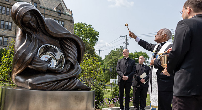 Washington Cardinal Wilton D. Gregory blesses the sculpture "Advent" by Canadian artist Timothy Schmalz on the grounds of Theological College in Washington May 17, 2023. The sculpture depicts Jesus as an unborn child in Mary's womb. (OSV News photo/Mihoko Owada, Catholic Standard)