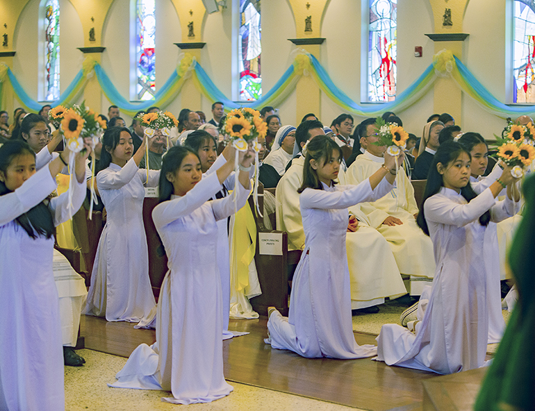 Las jóvenes de Our Lady of La Vang realizan un baile durante la Misa del 2 de julio de 2023, cuando el Arzobispo Thomas Wenski elevó formalmente la iglesia de la categoría de misión a la de parroquia para la comunidad vietnamita.