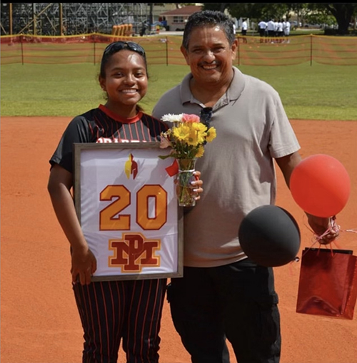 Jamie Argüello, co-captain of the Msgr. Edward Pace High School softball team, poses with her softball uniform beside her father, Jaime.