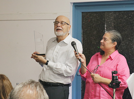 Juan José Rodríguez recibe una placa conmemorativa por sus 27 años al frente de la Pastoral Juvenil del Instituto Pastoral del Sureste, para el Ministerio Hispano, SEPI, durante una emotiva ceremonia. Lo acompaña Olga Villar, la directora ejecutiva del SEPI, el 15 de abril de 2023, en la sede del SEPI, en Miami.