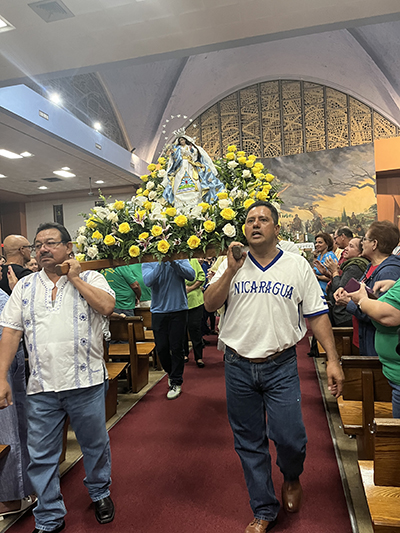 Alcides Membreno y Donald Alvarenga llevan en procesión a La Virgen de la Asunción sobre el volcán Cerro Negro, después de la Misa que se celebró el 15 de agosto 2023 en la iglesia St. John the Apostle, en Hialeah.