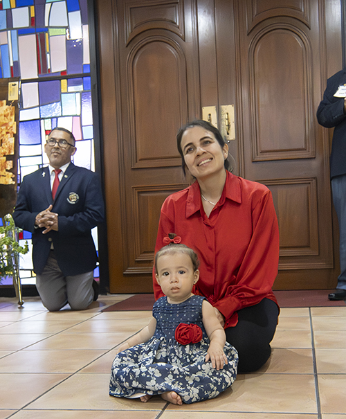 La niña Elena Sánchez sentada delante de su madre, Selena Bitter, durante la consagración de la Eucaristía en la Misa celebrada para conmemorar el 50 aniversario de la iglesia St. Benedict, el 23 de septiembre de 2023.