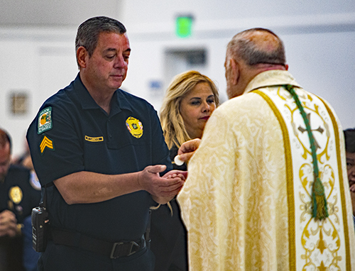 Sgt. Robert LaRicci from the Pinecrest police department receives Communion from Archbishop Thomas Wenski during the Blue Mass, Sept. 29, 2023, at Our Lady of Guadalupe Church in Doral.