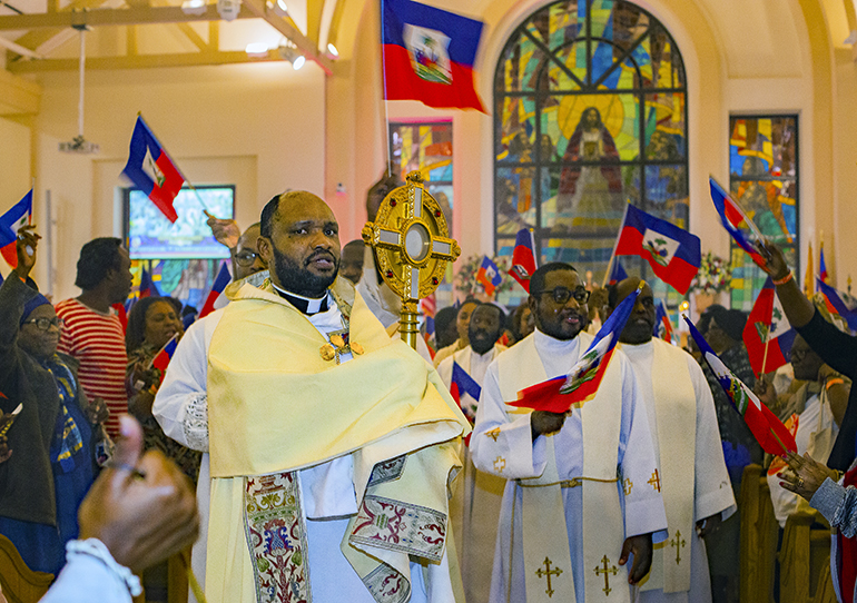 Father Luc Philogene carries the monstrance with the Blessed Sacrament as participants prepare to walk around Notre Dame d'Haiti Church in Miami at the conclusion of the third of seven nights of Jericho, Oct. 15-21, 2023.