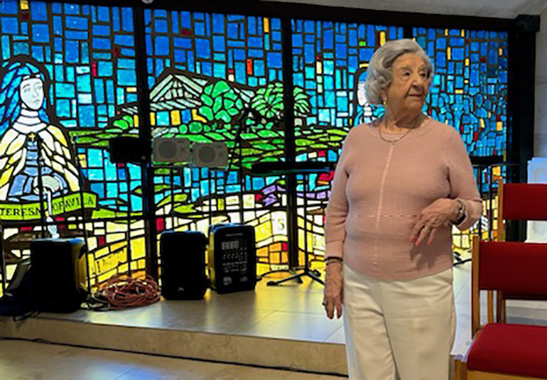 While celebrating her 100th birthday July 16, 2023, Muriel Conroy, center front, poses by the stained glass window she helped design in her longtime parish, St. Pius X in Fort Lauderdale.