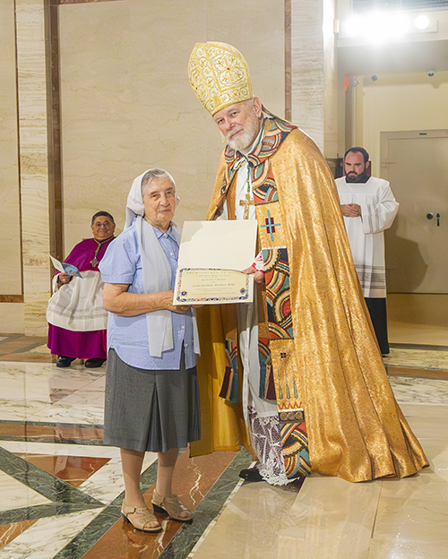 Claretian Sister Carmen Alvarez receives the Papal Cross Pro Ecclesia et Pontifice from Archbishop Thomas Wenski during the Archdiocese of Miami's 65th anniversary vespers service, Oct. 22, 2023, at St. Mary Cathedral.