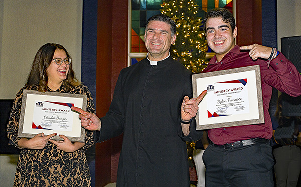 Father Rafael Capó, vice president of Mission at St. Thomas University, jokes with STU students Claudia Danger and Dylan Francisco after giving them each a Campus Ministry Award during the university's inaugural Ministry Awards dinner and celebration, held Nov. 29, 2023, on the Miami Gardens campus.