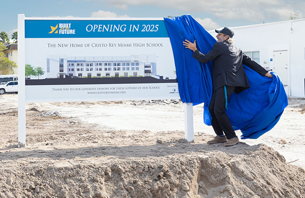 Nelson Castellanos, director of Operations at Cristo Rey Miami High School, unveils the sign depicting the exterior of the new academic building, projected to open in 2025, at the groundbreaking ceremony, Nov. 30, 2023.