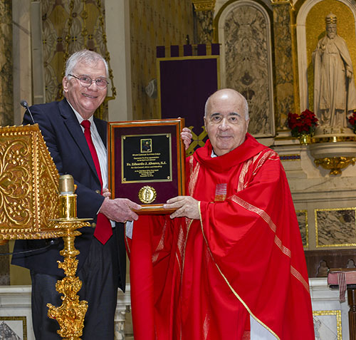 Frank Sexton, Jr., president of the Miami Catholic Lawyers Guild, gives a plaque to Jesuit Father Eduardo Alvarez, recently retired pastor of Gesu Church and the guild's spiritual advisor, at the conclusion of the annual Red Mass, celebrated Dec. 11, 2023, at Gesu by Archbishop Thomas Wenski.