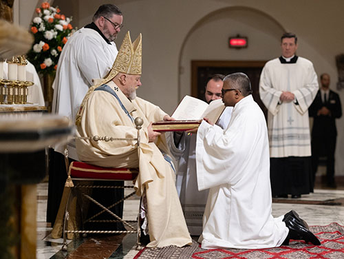 El Arzobispo Thomas Wenski entrega al diácono Srinath Perera el Libro de los Evangelios, "en cuyo heraldo te has convertido", el 16 de diciembre de 2023, en la catedral St. Mary.