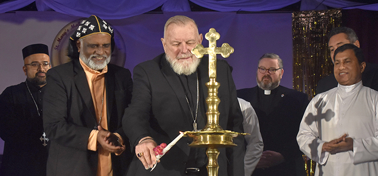 Archbishop Thomas Wenski lights a nilavilakku, a traditional Indian lamp, during a festival Jan. 14, 2024, with St. Mary's Syro-Malankara Church. The festival was held at Nativity Church in Hollywood. At left is Bishop Philipos Mar Stephanos Thottathil, head of Syro-Malankara Catholics in the U.S. and Canada.