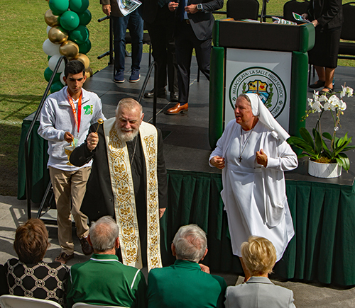 Archbishop Thomas Wenski blesses those present before blessing the new athletic facilities at Immaculata-La Salle High School as Salesian Sister Kim Keraitis, principal,  looks on, Feb. 1, 2024.