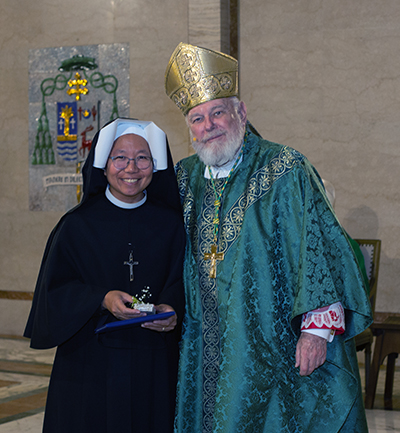 Archbishop Thomas Wenski gives Sister Maria Teresa of the Merciful Jesus, of the Schoenstatt Sisters of Mary, a certificate of appreciation to mark her 25 years of religious profession during the annual Mass for the World Day of Prayer for Consecrated Life, celebrated Feb. 3, 2024, at St. Mary Cathedral, Miami.