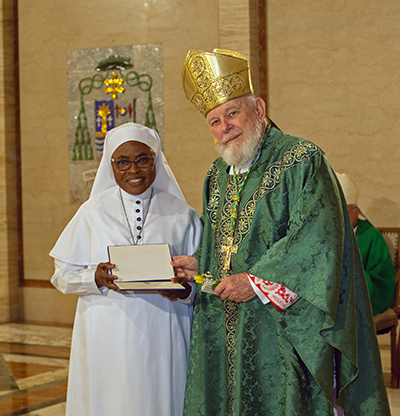 Archbishop Thomas Wenski gives Sister Maria Bernadette de Lourdes Dike, of the Daughters of Mary Mother of Mercy, a certificate of appreciation to mark her 50 years of religious profession during the annual Mass for the World Day of Prayer for Consecrated Life, celebrated Feb. 3, 2024, at St. Mary Cathedral, Miami.