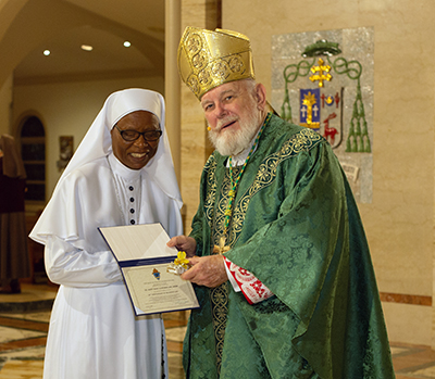 Archbishop Thomas Wenski gives Holy Rosary Sister Mary Rose Ekwebbelam a certificate of appreciation to mark her 50 years of religious profession during the annual Mass for the World Day of Prayer for Consecrated Life, celebrated Feb. 3, 2024, at St. Mary Cathedral, Miami.