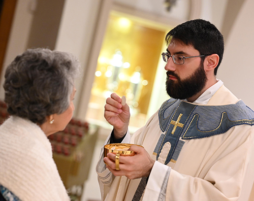 Newly ordained Father David Zallocco gives communion during the Mass where Archbishop Thomas Wenski ordained him and three others, May 11, 2024 at St. Mary Cathedral.