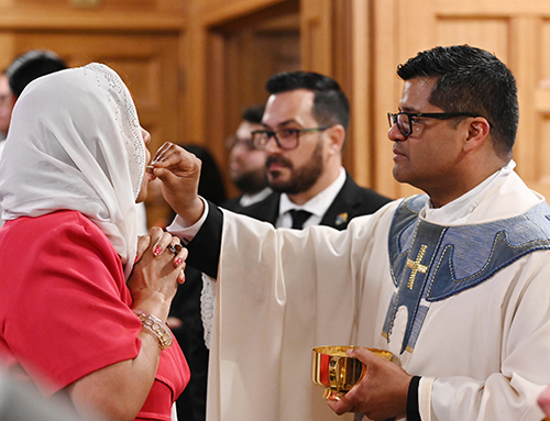 Newly ordained Father Milton Martinez gives communion during the Mass where Archbishop Thomas Wenski ordained him and three others, May 11, 2024 at St. Mary Cathedral.
