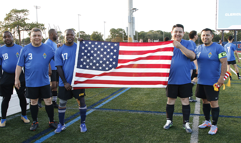Priests of the Archdiocese of Miami hold up the American flag before the presentation of the teams at the Clericus Cup International soccer match between priests of the Archdiocese of Miami and priests from the Archdiocese of Quito, Ecuador. The game was played April 23, 2024 on the soccer field at St. Thomas University in Miami Gardens. From left to right are Father Rinkinson Bantou, Father Angel Calderon, Father Reynold Brevil, Father Pedro Torres, and Father Antonio Tupiza.