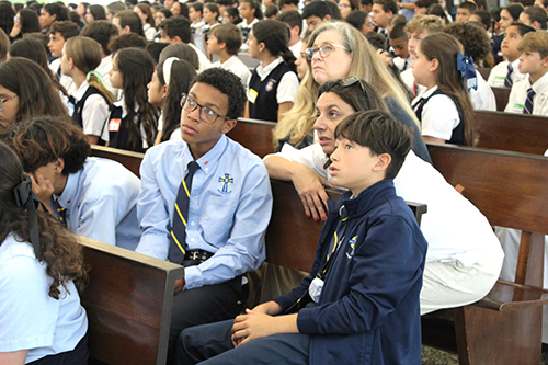Students Damian Glover (left) and Michael Perez, along with their teacher Ianne Lopez, of Our Lady of the Holy Rosary-St. Richard School in Cutler Bay, reflect on the mural above the sanctuary of St. Raphael Chapel before Mass for the Focus 11 vocation rally at St. John Vianney College Seminary, May 21, 2024.