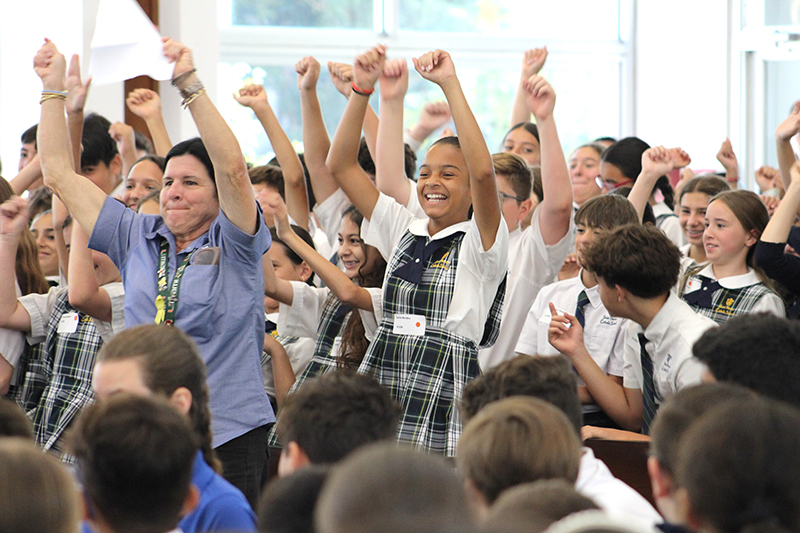 Students from St. Theresa School in Coral Gables, and their aide teacher Ana Cairo, stand up and silently cheer during the archdiocesan school roll call at the Focus 11 vocations rally on May 21, 2024, in St. John Vianney College Seminary.