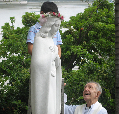 El P. Amando Llorente junto a la Virgen de la Agrupación Católica Universitaria, imagen del escultor Carbonell, réplica de la que se venera en la casa de La Habana.